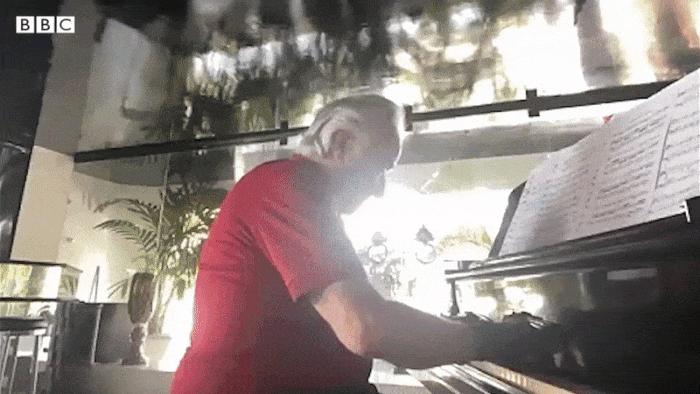 old man playing piano in gloves